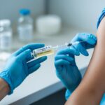 Profissional de saúde segurando uma seringa para aplicar vitamina B12 injetável no braço de um paciente.